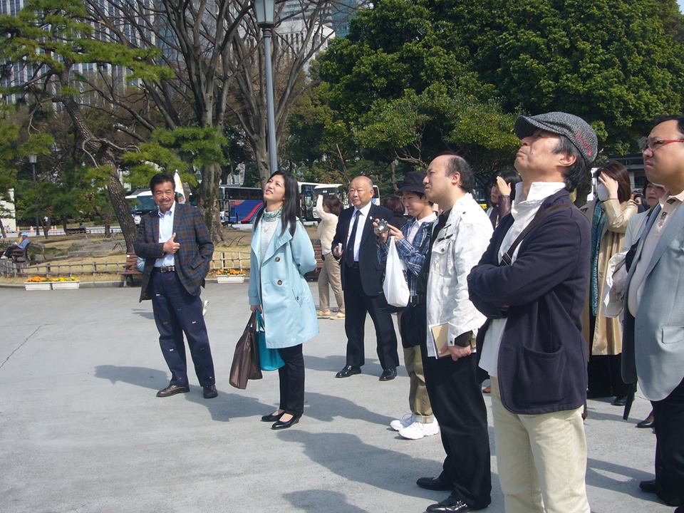ブルーのコートを着た会長・瀧島が、江戸ツアー参加者の皆さんへ楠公像の説明をしています。